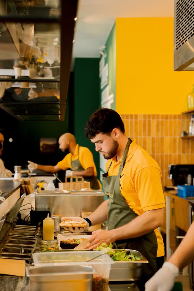 Two of the KALIMERA team preparing wraps at the counter in the Bordeaux kitchen