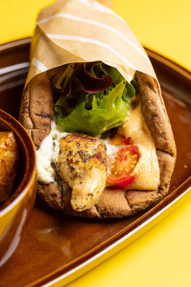 A souvlaki wrap up close: wholemeal pita, chicken, tzatziki, tomato and green salad