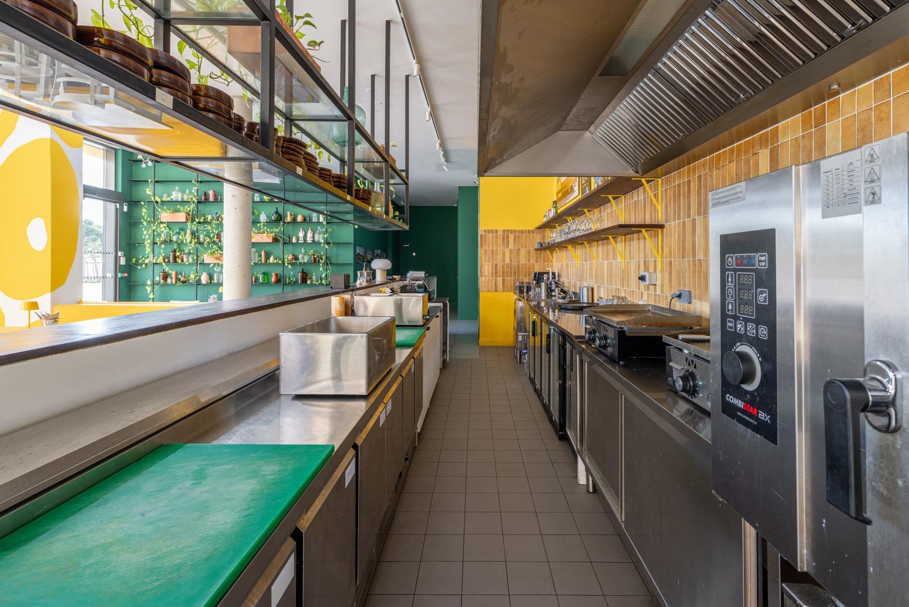 The kitchen at KALIMERA Bordeaux, where the workshops take place: steel counters, green chopping boards and a wall of yellow tiles